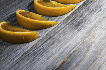 Side view of sliced orange slices poggiatu with background of an old black wooden board