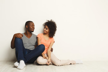 Fototapeta na wymiar African-american couple looking up, sitting on floor
