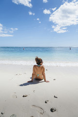 Young woman looks at the horizon sitting on a beach of Mauritius Island in the summer