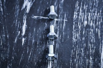 Nuts for repairs lying on a wooden table. Iron nuts and screws f