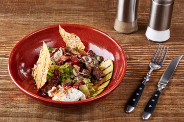 Salad from different kinds of sausages, cucumbers, peppers, lettuce with sour cream sauce