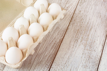 Cardboard egg rack with eggs on white wooden table