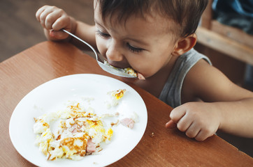 Cute Asian child eating breakfast in a restaurant