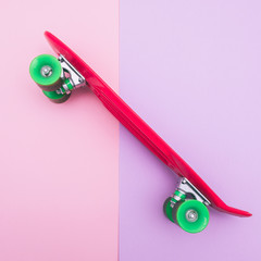 skateboard with green wheels on pink and purple background. pastel creative concept. minimalism
