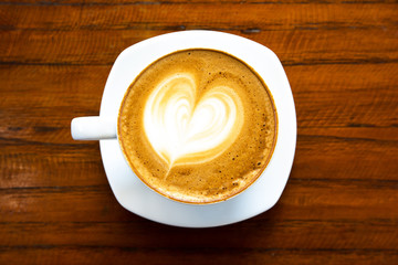 Top view of hot coffee latte cappuccino foam in white coffee cup on wooden table background