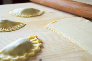 preparation of Christmas cakes (half moons) with pasta dough and rolling pin on a wooden background