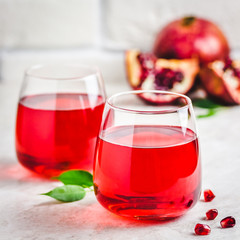 Pair of glasse with pomegranate juice on white marble background. Selective focus, copy space.