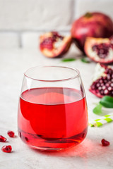 A glass with fresh pomegranate juice on white marble background. Selective focus, copy space, close up.