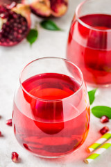 Two glasses with pomegranate juice on white marble background. Selective focus, copy space.