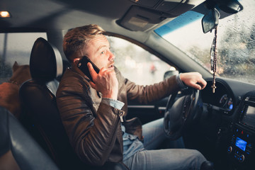 Handsome young man driving his car and speaking on the cellphone.