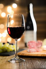 glass of red wine with french cheese and delicatessen in restaurant wooden table with romantic dim light and cosy atmosphere