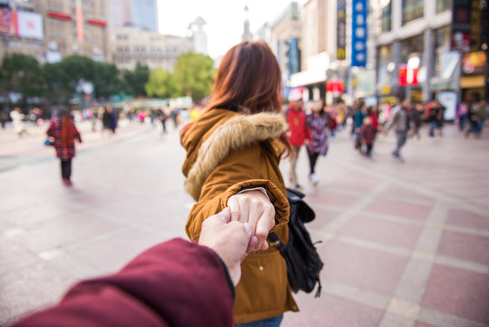 Traveling Together. Follow Me. Rear View Of Woman In Jacket Clothes Leading Man To The Nanjing Road Shopping Street In Shanghai.