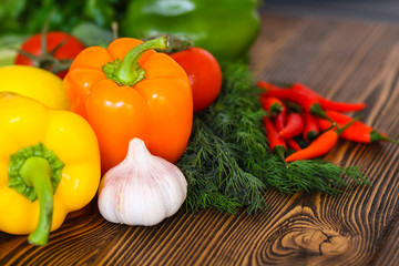 Fresh tasty vegetables. Tomatoes, sweet peppers, broccoli, garlic, dill, parsley. On a wooden background.