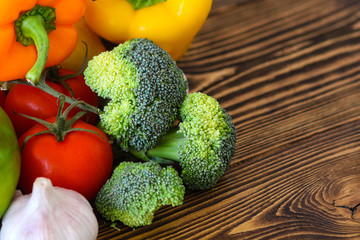 Fresh tasty vegetables. Tomatoes, sweet peppers, broccoli, garlic, dill, parsley. On a wooden background.