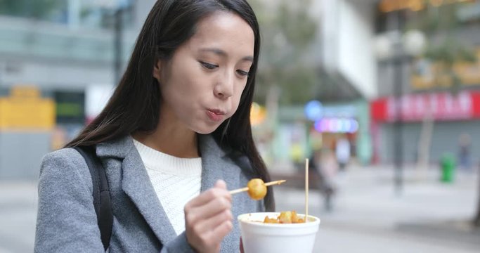 Woman eating fish ball, Hong Kong style snack