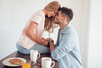 Cute young couple drinking coffee in kitchen.