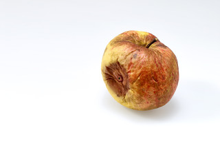 Alter Apfel mit runzeliger Schale und Wurm