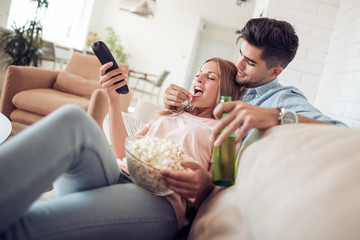 Couple watching TV and eating popcorn.