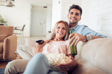 Obraz na płótnie Canvas Couple watching TV and eating popcorn.