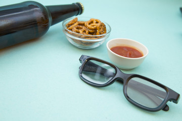 Weekend, Leisure, Lifestyle Concept. Ready to have fun, 3d glasses, a bottle of beer deliciuos pretzels and ketchup on a light blue background, close up
