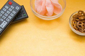 Weekend, Leisure, Hobby Concept. Weekend with movies, two remote controls, pretzels and shrimp chips on a light orange background, flat lay