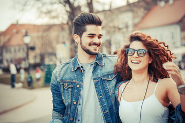 Young couple laughing and walking at the city downtown.They embrace each other and smiling.