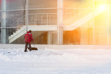 A worker clears snow after a snowstorm in front of a large office building..