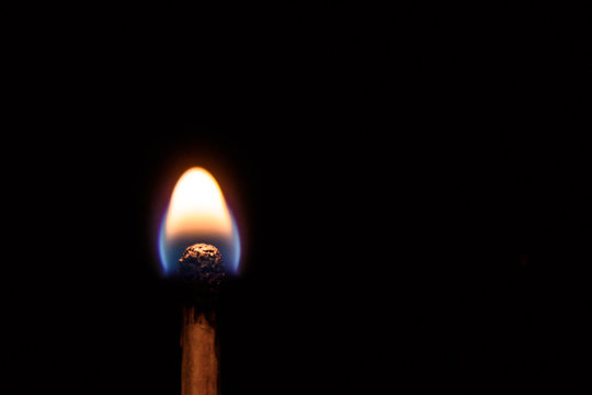 Match with a very weak, discontinuous flames on a black background closeup