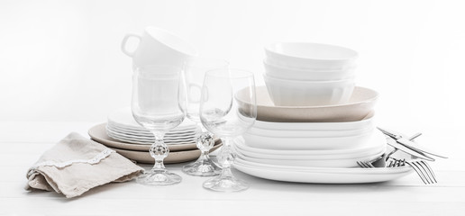 Stack of mixed white dishes and crystal glasses