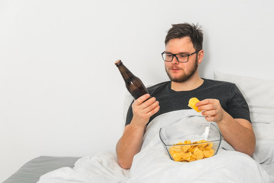 man in bed with beer and snacks