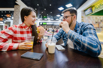 couple make pause for shopping eat burgers in mall cafe