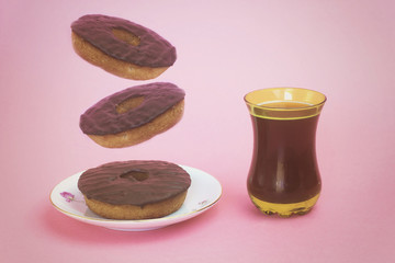 homemade flying chocolate arabic donuts with turkish tea on pink background