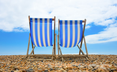 two wooden deck chairs at the beach