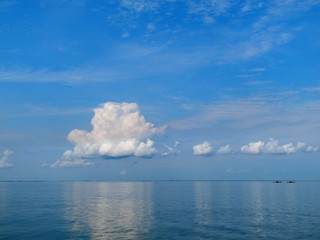 Naklejka premium View of a beautiful calm blue sea and sky with clouds and two man in kayaks in foreground