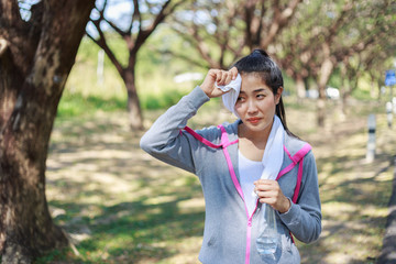 sporty woman resting and wiping her sweat with a towel after workout sport exercises outdoors at the park