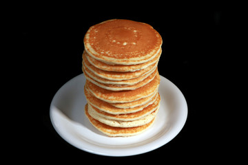 Tall stack of pancakes set against a black background