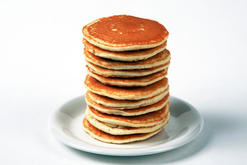 Tall stack of pancakes set against a white background