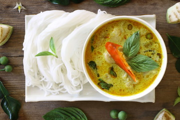 Top view of green curry fish ball served with Thai rice vermicelli in white plate on wood table, look delicious.