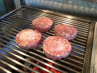 Four burgers grilling