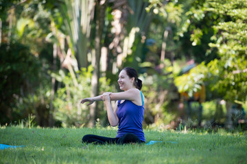 Young woman a smile practicing yoga in the park outdoor. Concept of healthy lifestyle and relaxation.