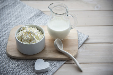 Milk and cottage cheese on a light wooden background
