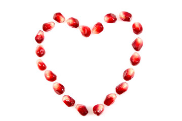 Fresh raw seeds of pomegranate fruit with heart symbol isolated on white background, Heart symbol made from seeds of pomegranate fruit on white background, with clipping path
