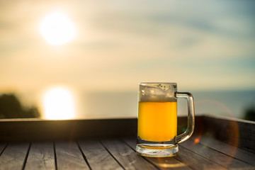 Mug with a light beer on the nature at sunset on a natural seaview background