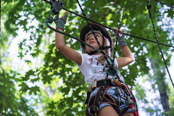 young girl in a rope park in the summer to overcome the obstacle course
