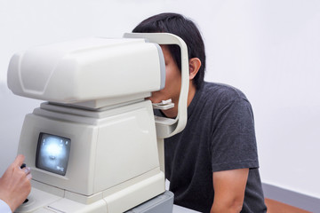 Young handsome asian man take eye exam with optical eye test machine