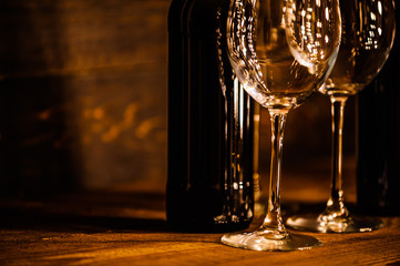 bottles with red wine and wine glasses on a wooden surface