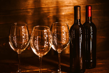 bottles with red wine and wine glasses on a wooden surface