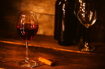 bottles with red wine and wine glasses on a wooden surface