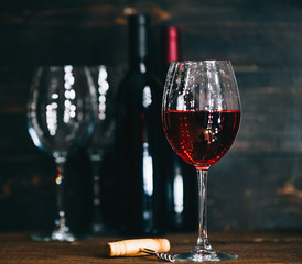 bottles with red wine and wine glasses on a wooden surface