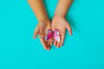 Little girls hands holding butterfly, on blue background